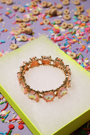 Bracelet with colorful charms on a box surrounded by cereal and sprinkles