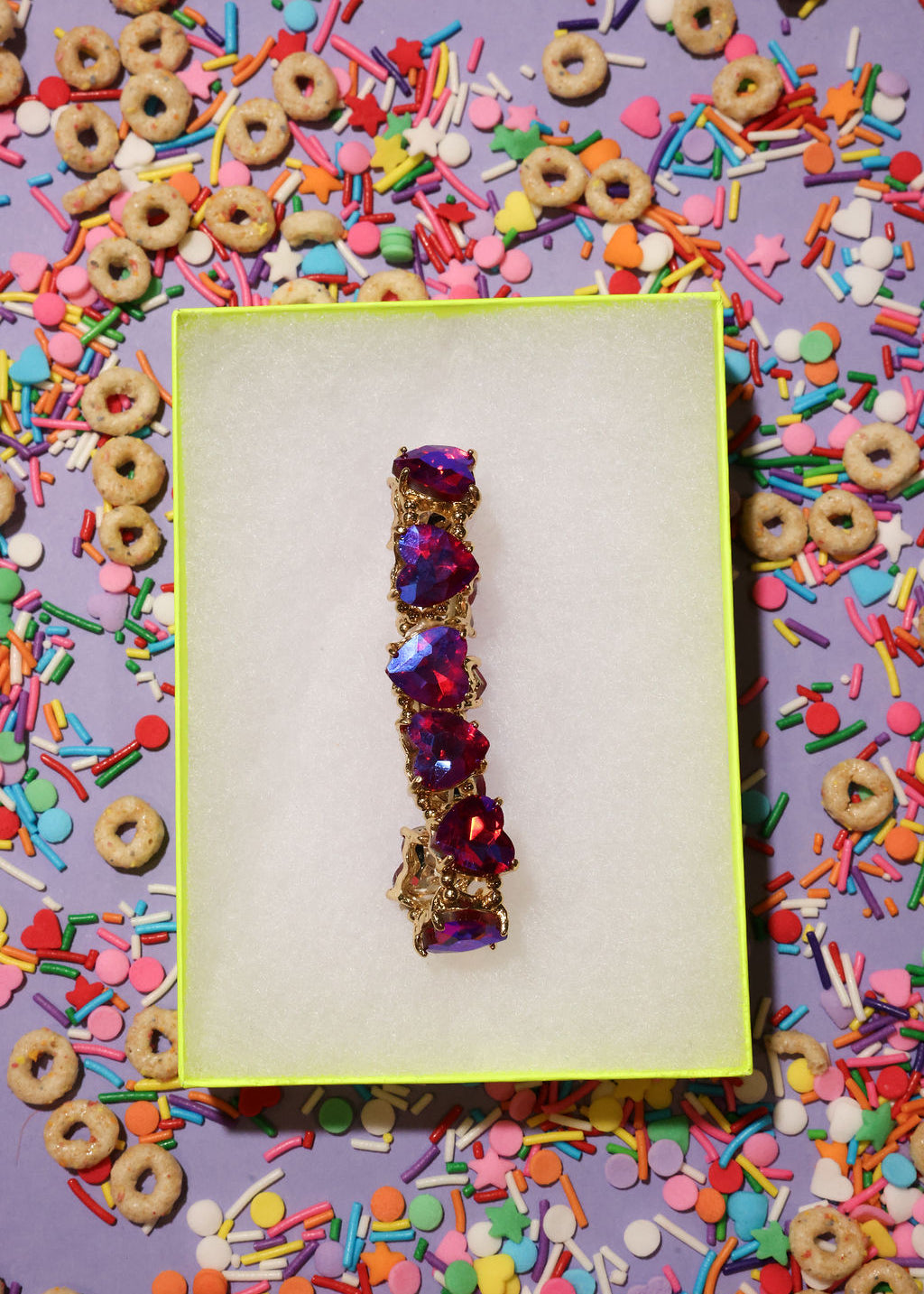 Jewelry box with a decorative bracelet on a colorful background of sprinkles and cereal.