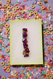 Jewelry box with a decorative bracelet on a colorful background of sprinkles and cereal.