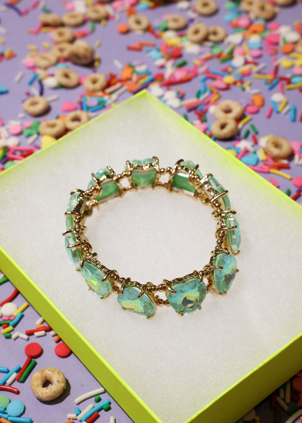 Turquoise beaded bracelet on a yellow box with colorful cereal and sprinkles in the background
