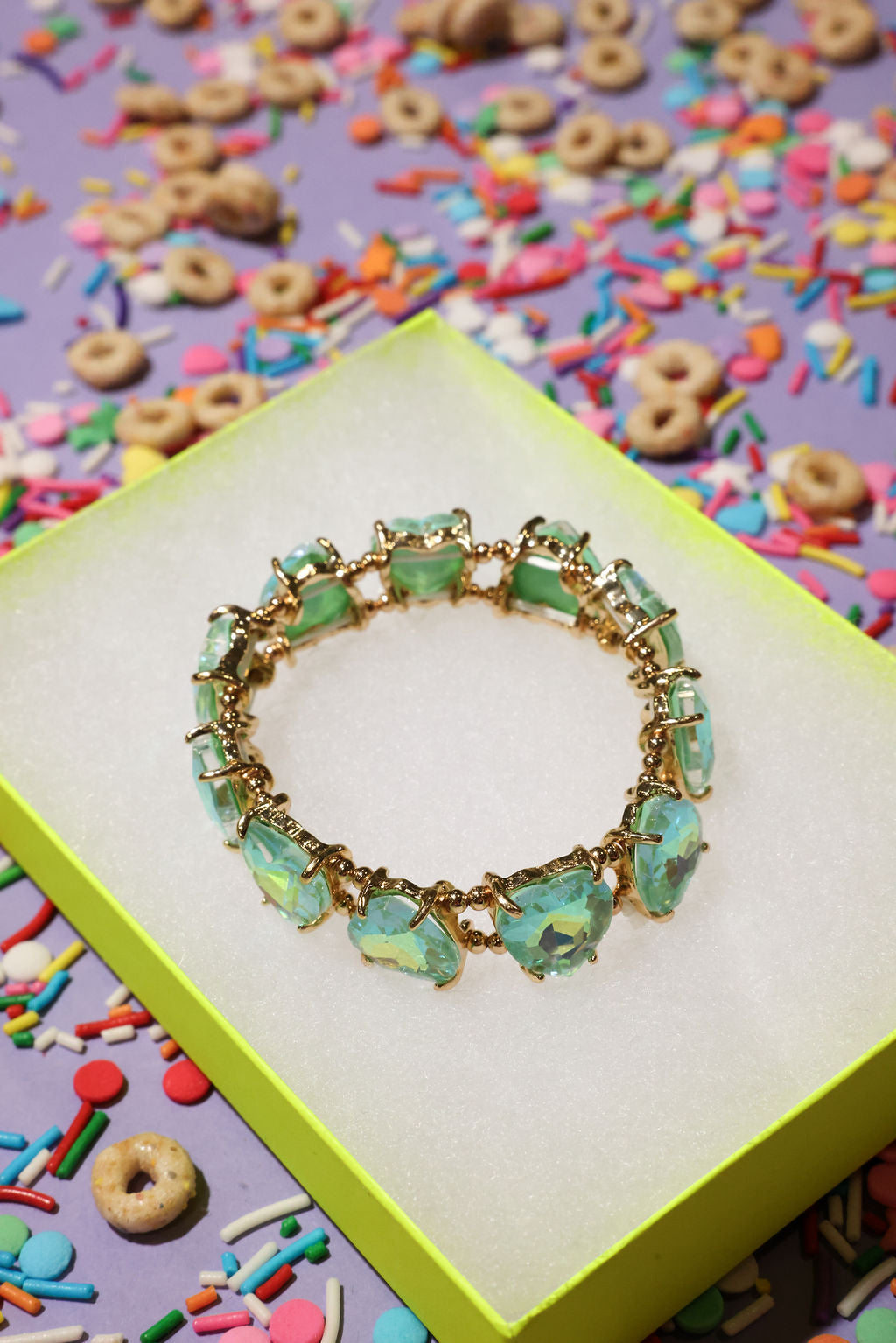 Turquoise beaded bracelet on a yellow box with colorful cereal and sprinkles in the background