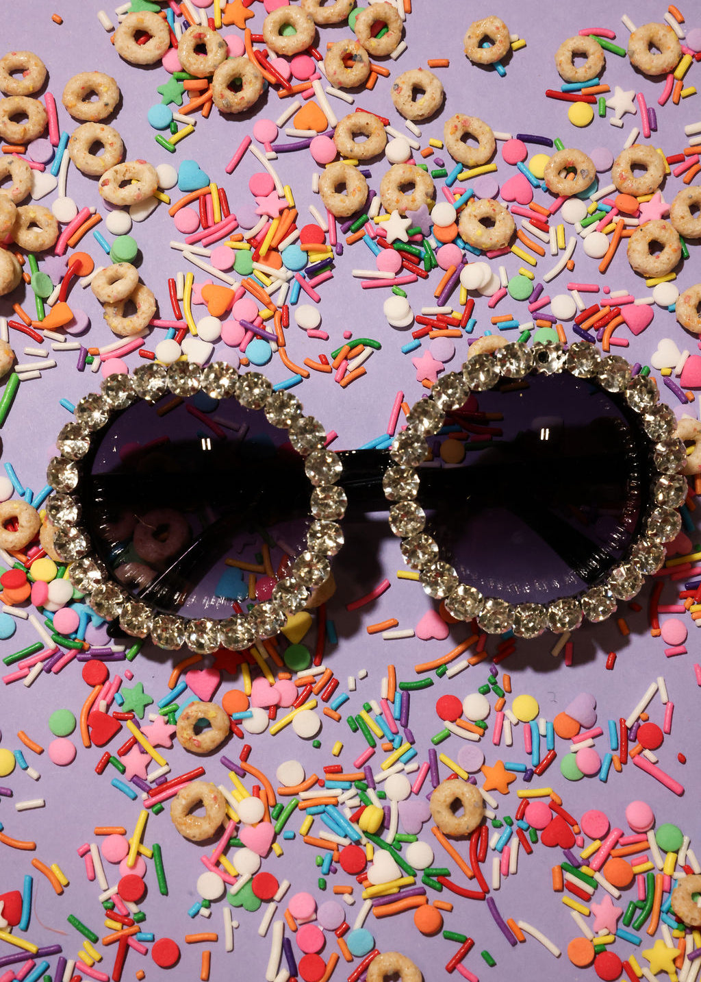 Decorative sunglasses with rhinestones on a colorful sprinkles and cereal background