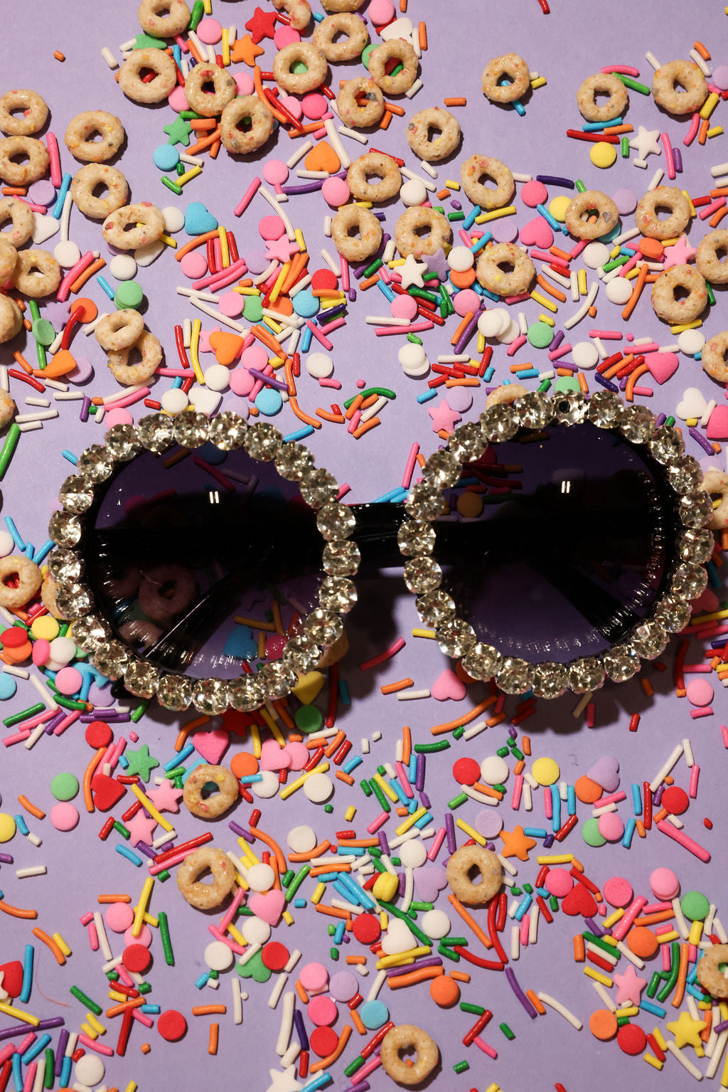 Decorative sunglasses with rhinestones on a colorful sprinkles and cereal background