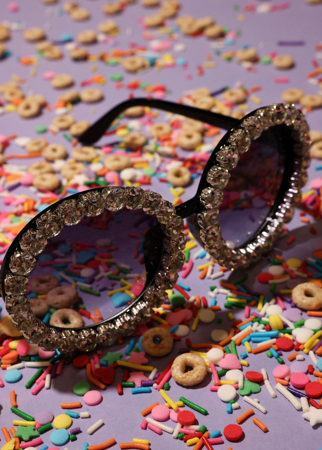 Decorative sunglasses with diamond frame on a colorful cereal and sprinkles background