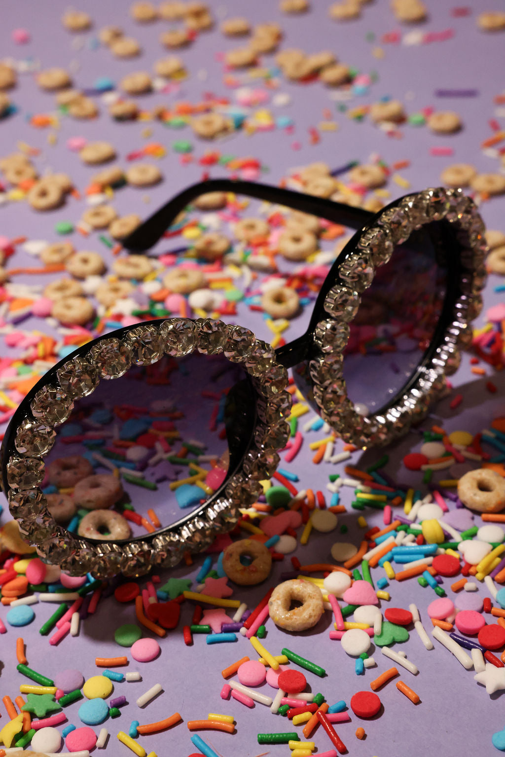 Decorative sunglasses with diamond frame on a colorful cereal and sprinkles background