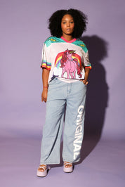 Model wearing a colorful mesh short sleeve jersey with a unicorn and rainbow design, denim pants, on a purple background, frontal view