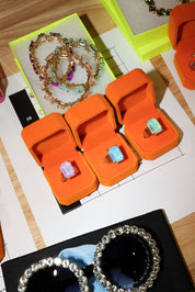 Orange jewelry boxes with gemstone rings on a table