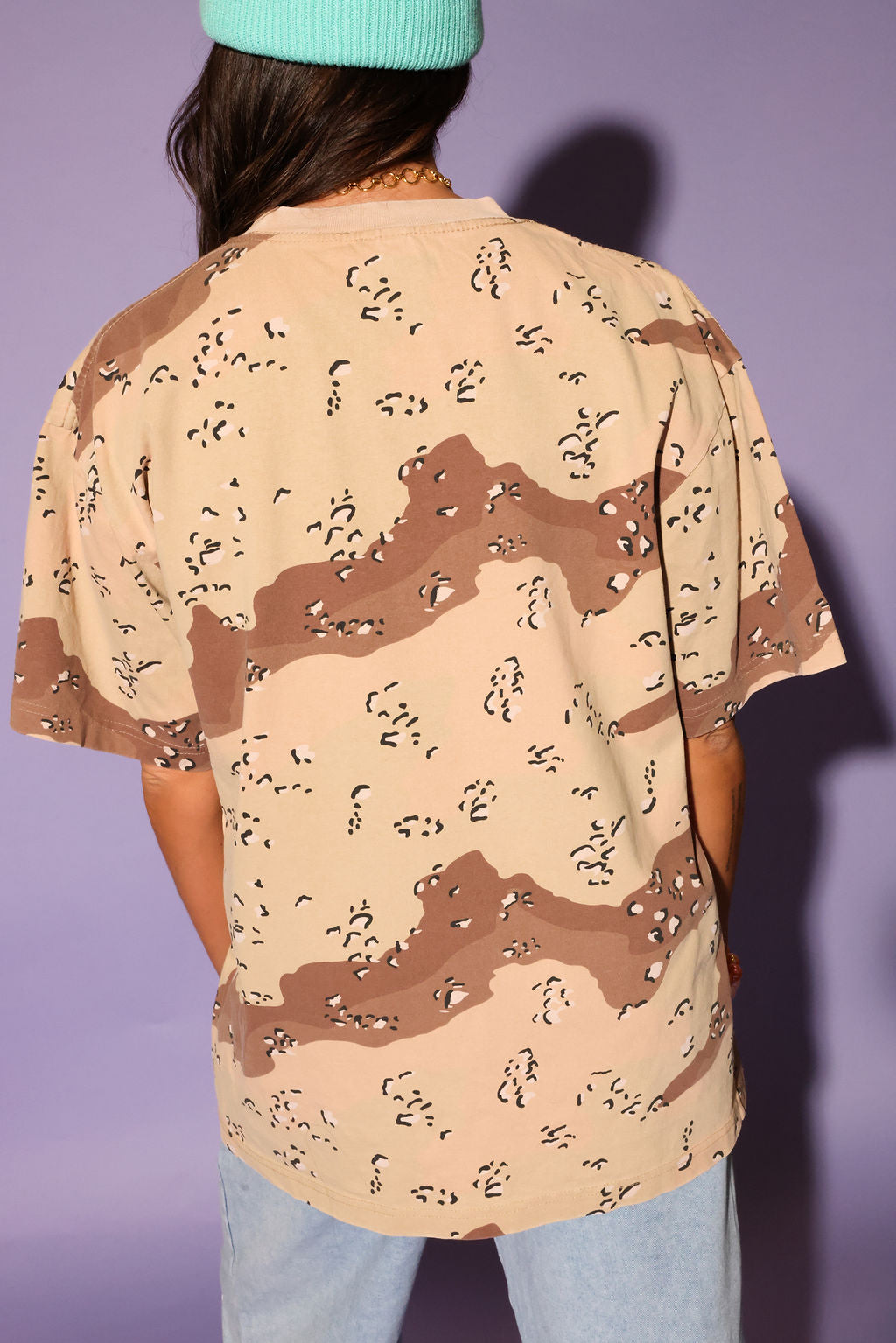 Person wearing a camouflage-patterned shirt with a plain background, back view