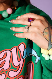 Close-up of a hand with jewelry on a green garment with colorful designs