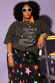 Woman wearing a grey t-shirt with colorful text and a star-patterned skirt against a purple background, frontal view