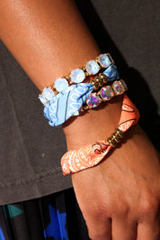 Close-up of a wrist wearing multiple colorful bracelets on a dark background