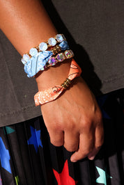 Close-up of a hand wearing colorful bracelets with a dark background