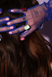 Close-up of hands with blue gloves and colorful rings on a blurred background