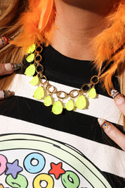 Neon green necklace with black accents worn by a person with orange hair, against a colorful background.
