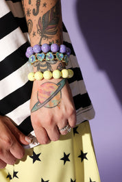 Person wearing colorful bracelets on a striped shirt and star-patterned pants