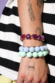 Wrist with colorful bracelets on a black and white striped background