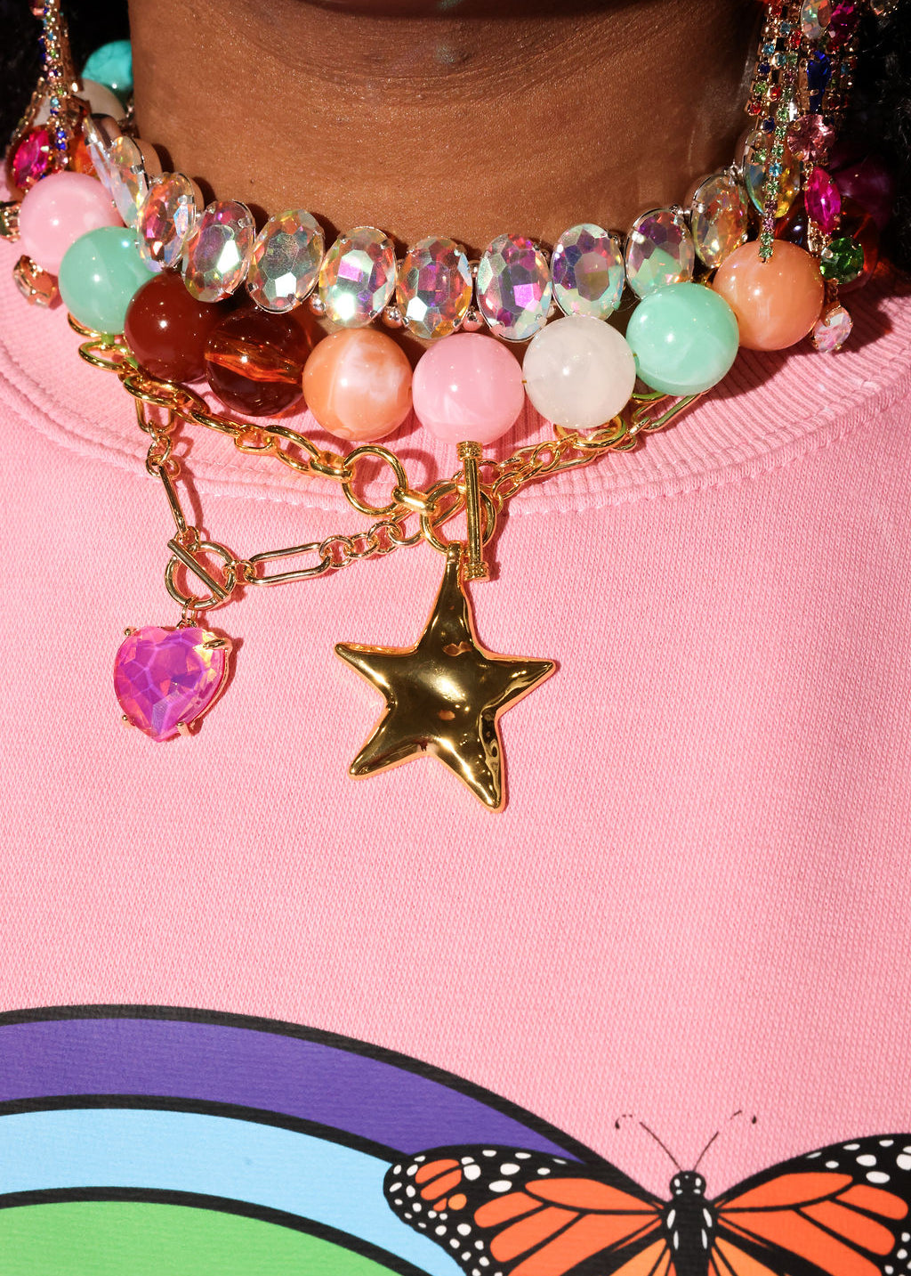 Close-up of colorful beaded necklace with star charm on pink background with butterfly design