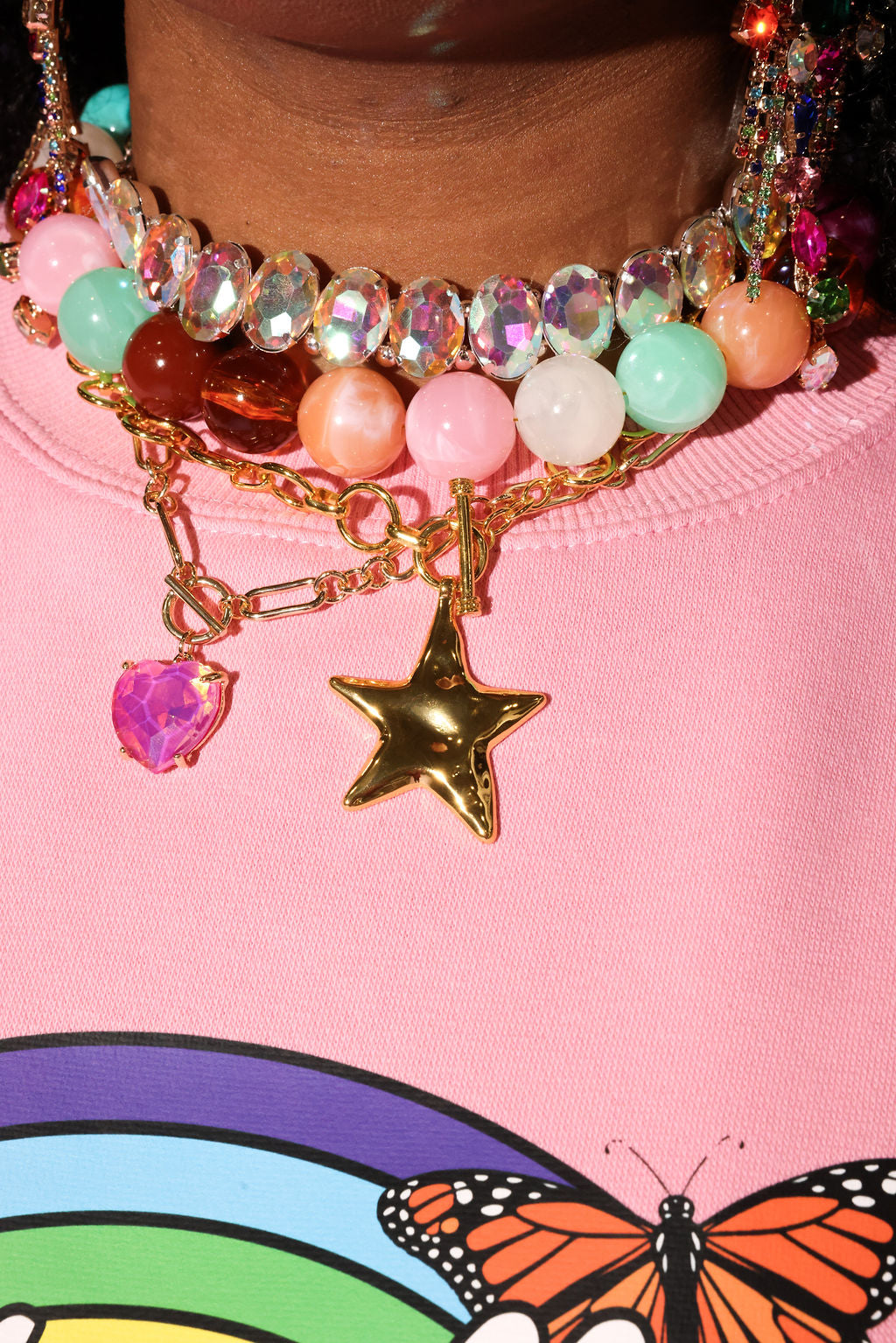 Close-up of colorful beaded necklace with star charm on pink background with butterfly design