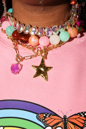 Close-up of colorful beaded necklace with star charm on pink background with butterfly design