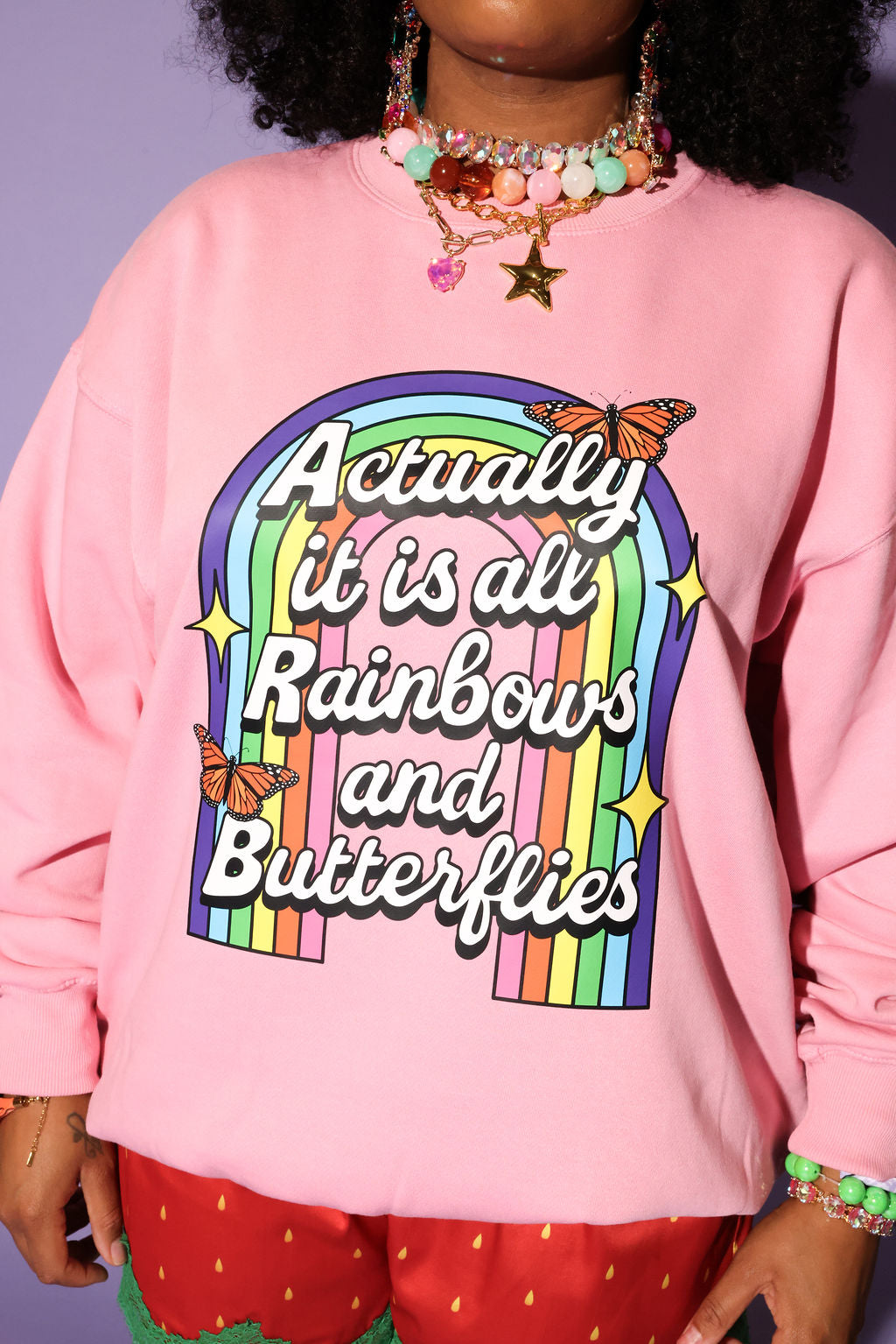 Person wearing a pink sweatshirt with rainbow text and butterfly graphics
