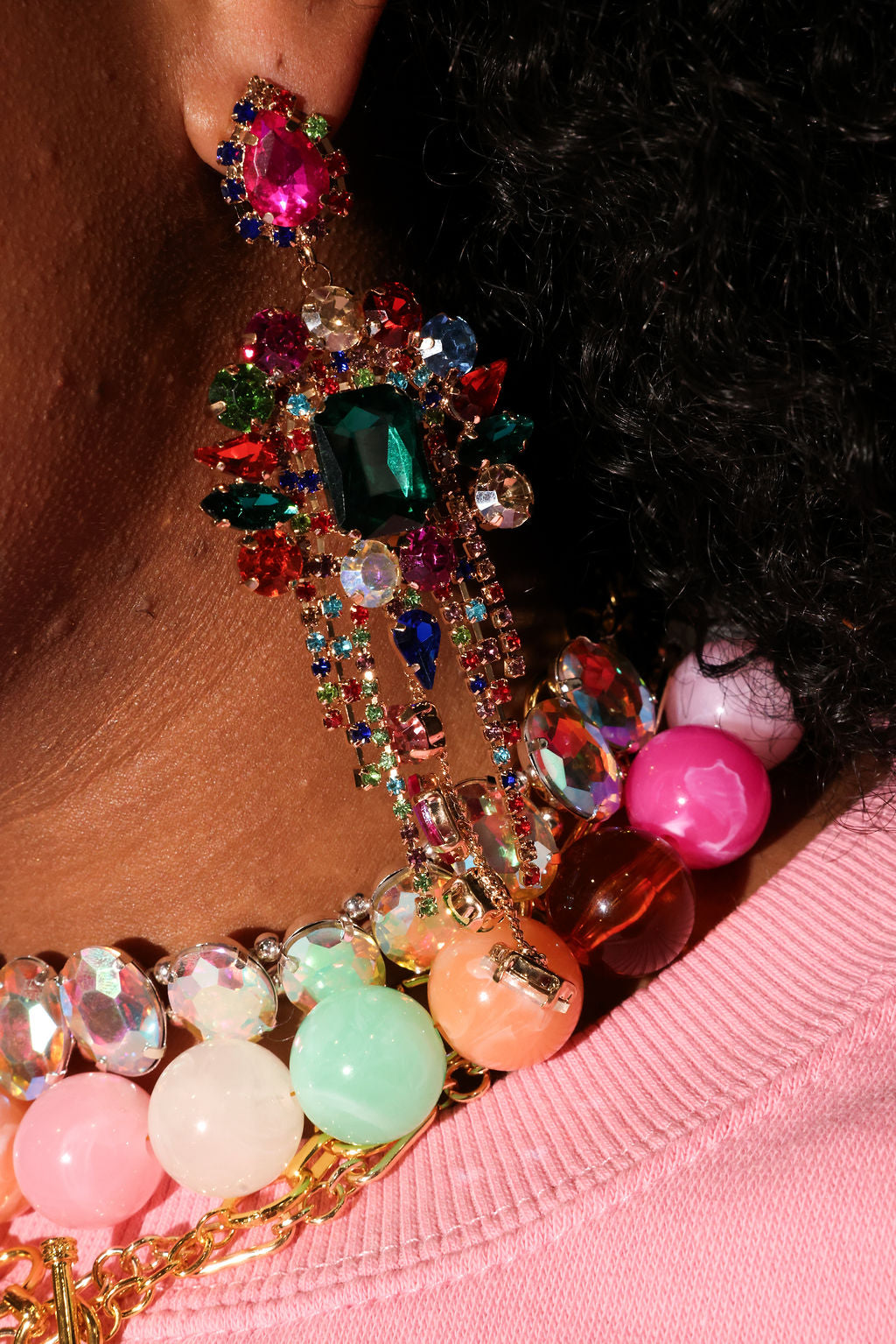 Close-up of colorful beaded earring with gemstones on a pink surface
