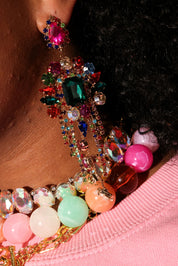 Close-up of colorful beaded earring with gemstones on a pink surface