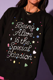 Black sweatshirt with colorful text and decorations on a purple background