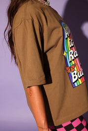 Person wearing a brown t-shirt with a colorful graphic design on a purple background, side view