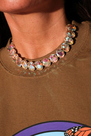 Close-up of a person wearing a colorful beaded necklace on a brown shirt with a butterfly design
