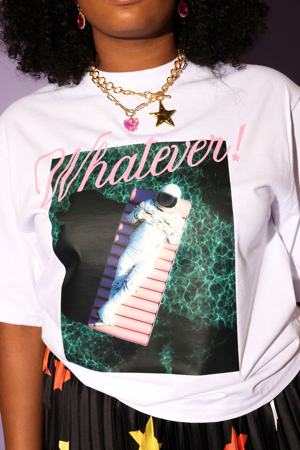 Person wearing a white sweatshirt with a graphic design and text 'Whatever!' on a dark background, close up view