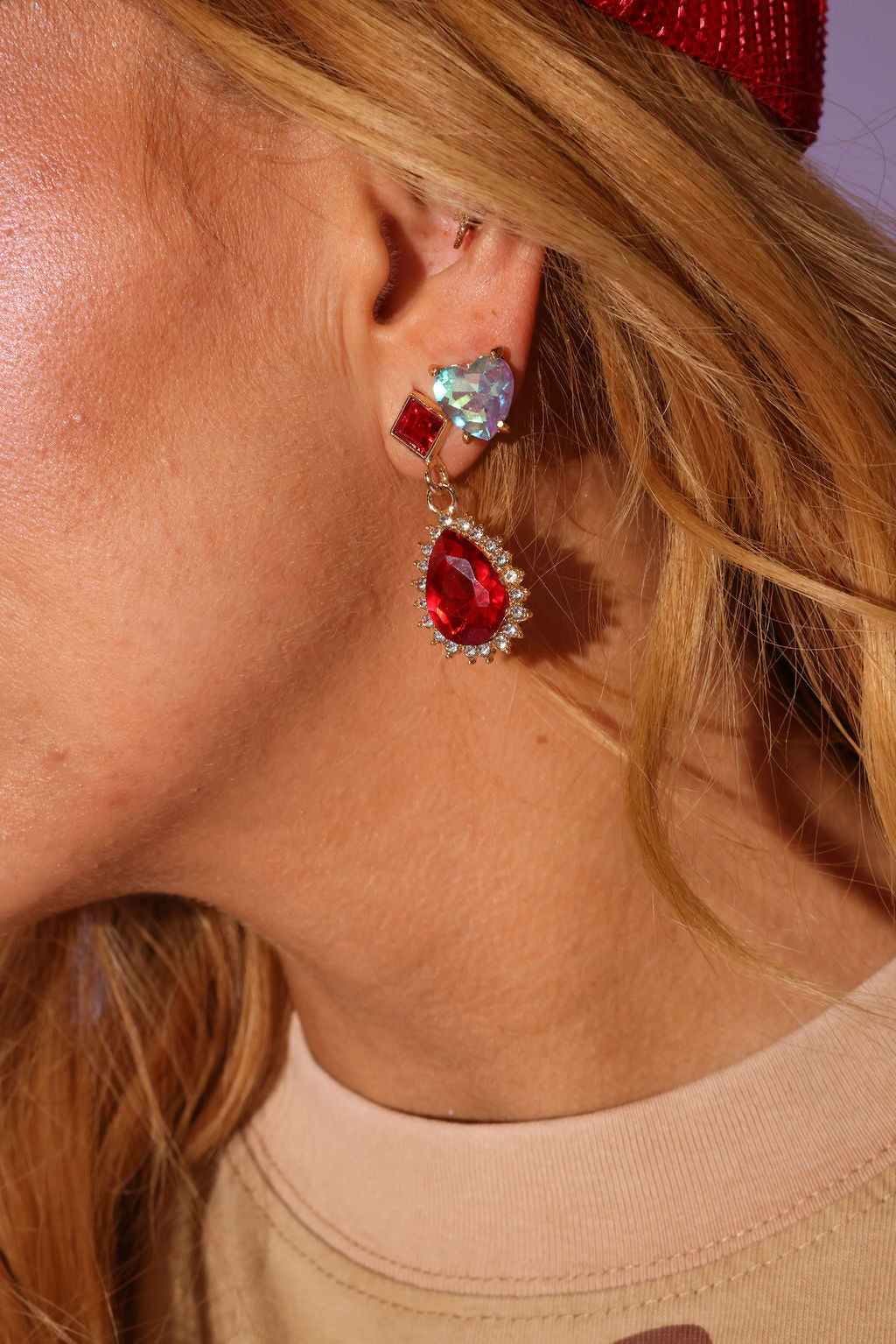 Close-up of a person wearing red and clear gemstone earrings.