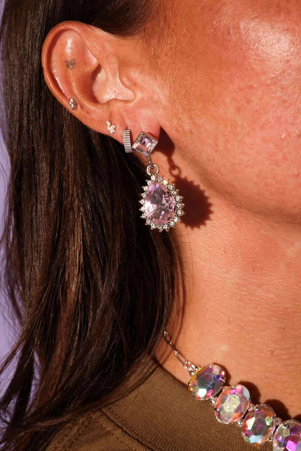 Close-up of a person wearing a sparkling earring with a pink gemstone