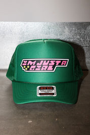 A green trucker hat with a mesh back and a front patch that reads 'I'M JUST A GIRL' in pink and white with small yellow stars. A smaller 'OTTO' brand patch is visible on the brim