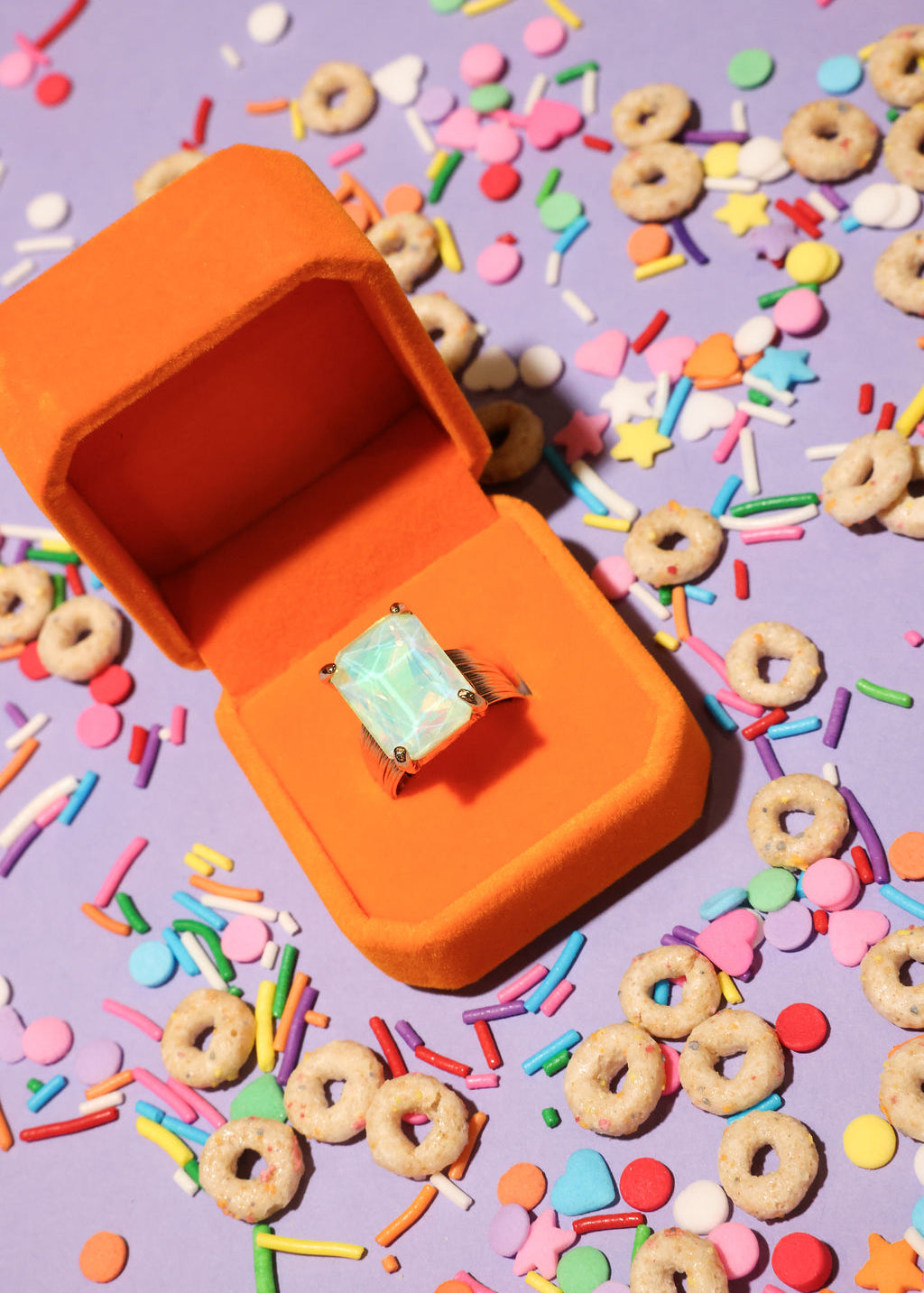 Opal ring in an orange box on a colorful cereal and sprinkles background