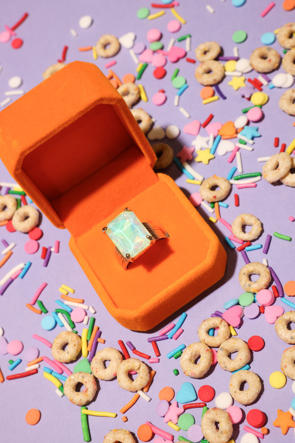 Opal ring in an orange box on a colorful cereal and sprinkles background