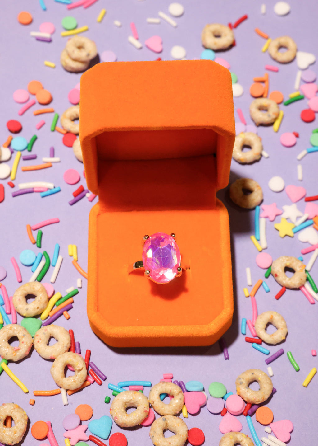 Orange ring box with a pink ring on a colorful background
