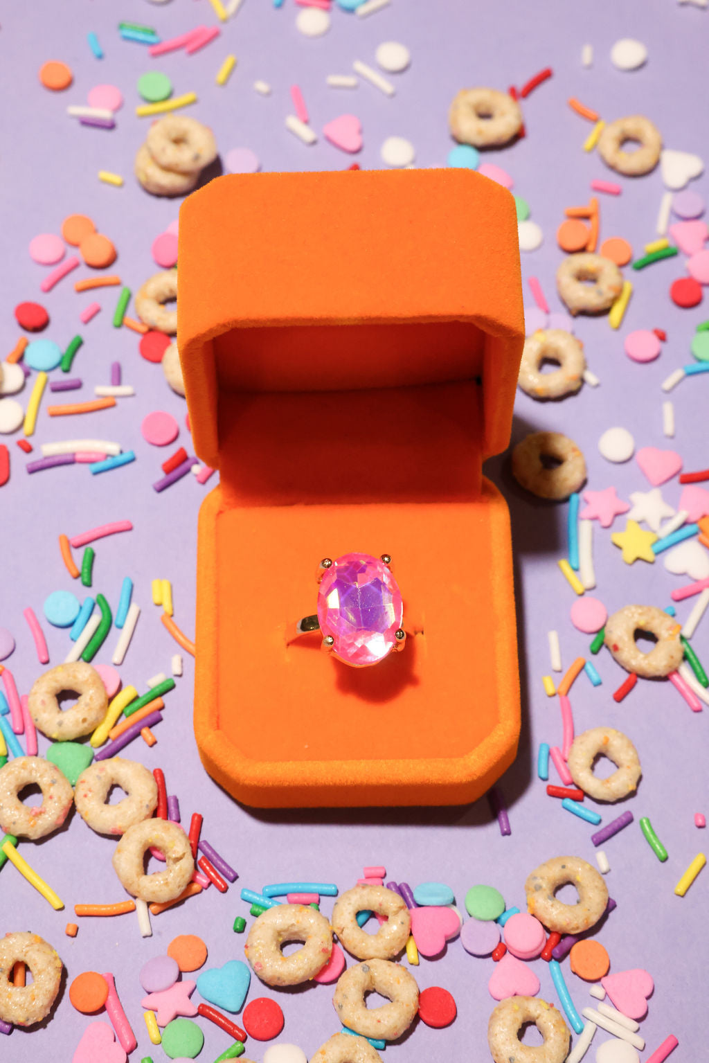 Orange ring box with a pink ring on a colorful background