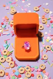 Orange ring box with a pink ring on a colorful background