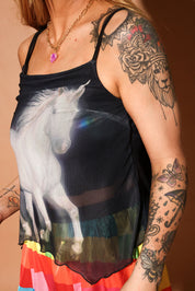 Model wearing a tank top with a unicorn design and colorful skirt, showcasing tattoos on arms, close up side view