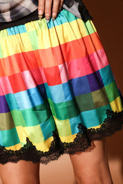 Colorful checkered satin shorties with black lace trim on a plain background, close up view