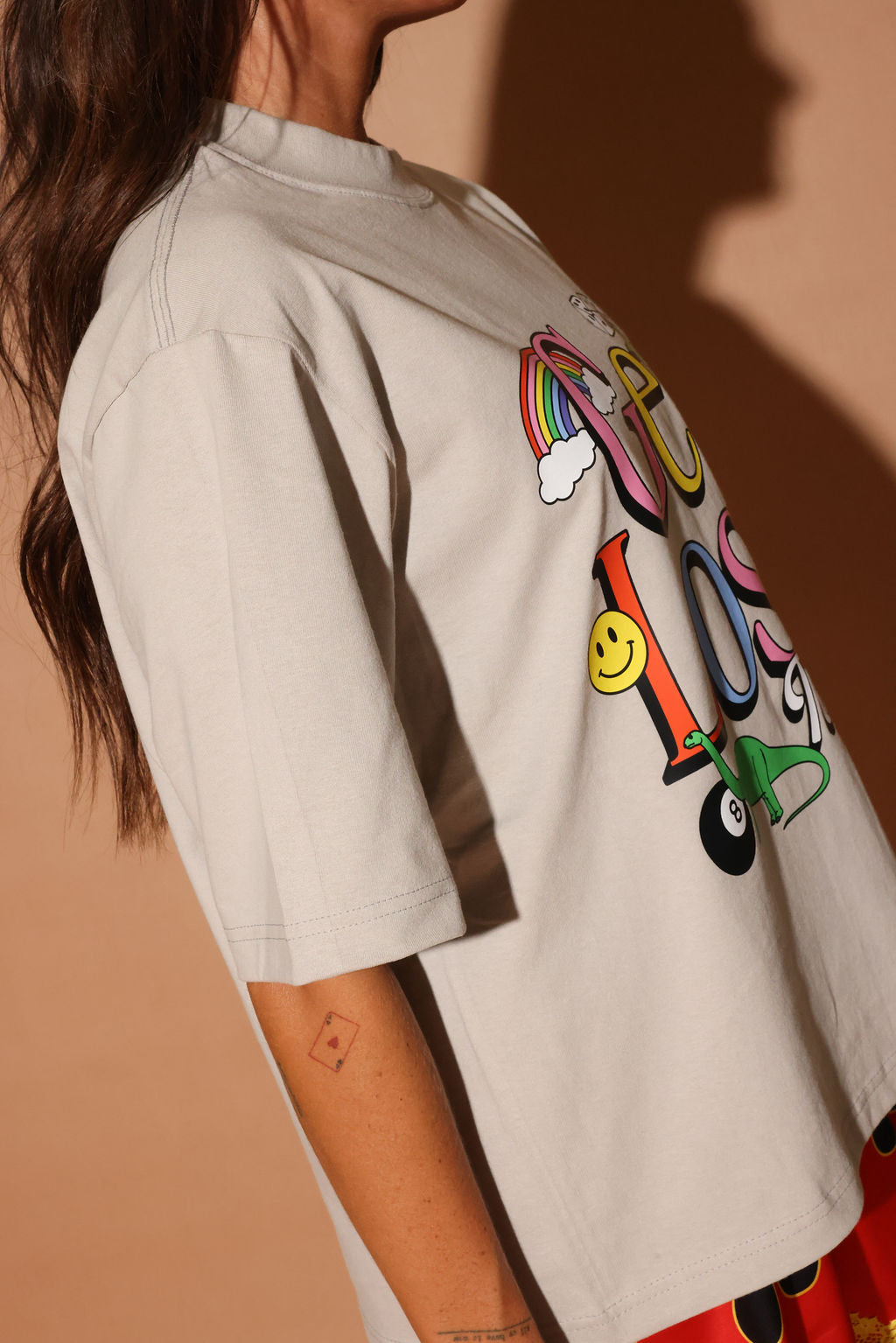 Beige shirt with colorful design on a plain background, side view