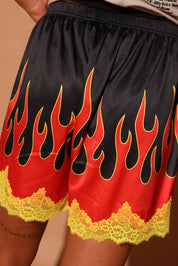 Black shorts with red and yellow flame design on a brown background, back view