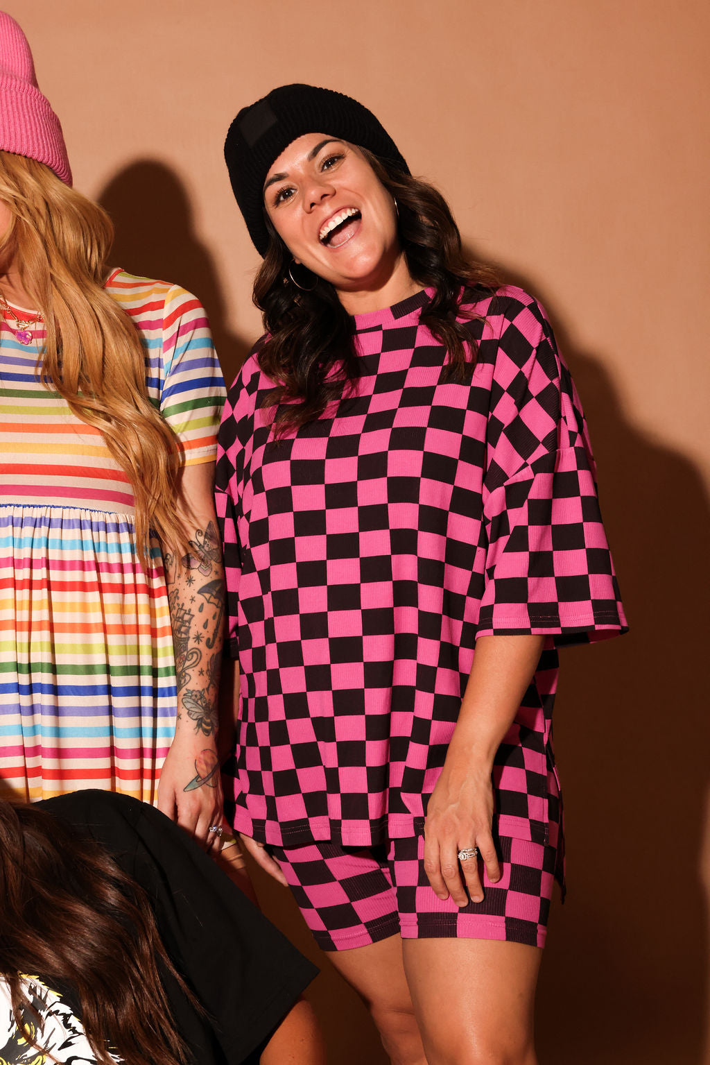 Woman wearing a pink and black checkered dress standing against a brown background