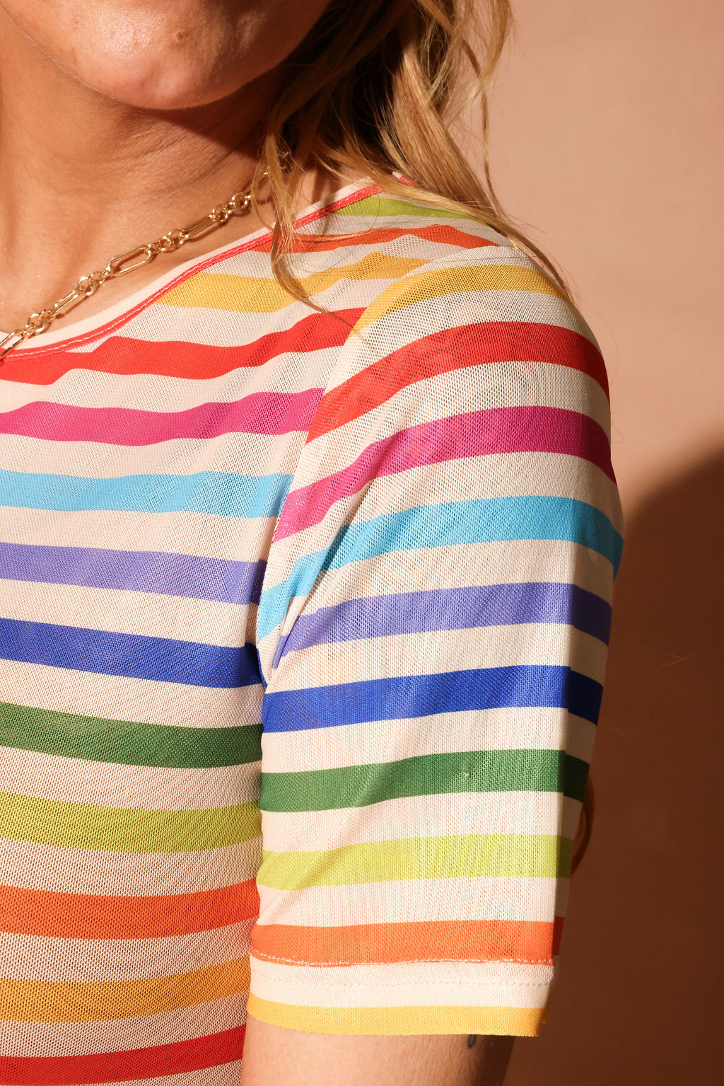 Close up of a woman wearing a colorful striped short dress focus on sleeve