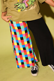 Model wearing a utility green graphic tee with a  graphic and colorful pants on a yellow background, close up of pants