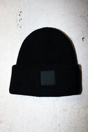A black beanie with a burnt toast label on a white textured background