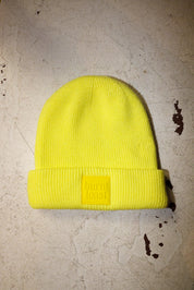 Yellow beanie with a Burnt Toast tag on a white textured surface