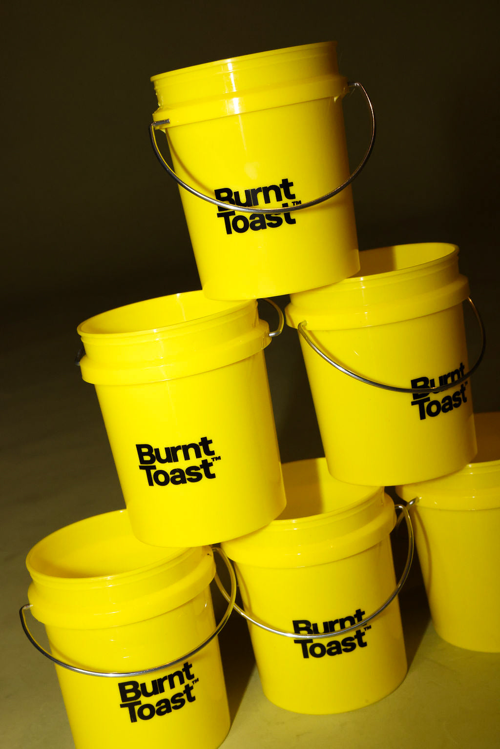 A pyramid stack of yellow buckets with a black Burnt Toast logo