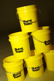 A pyramid stack of yellow buckets with a black Burnt Toast logo