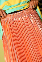 Close up a model holding the waistband of a peach plisse skirt